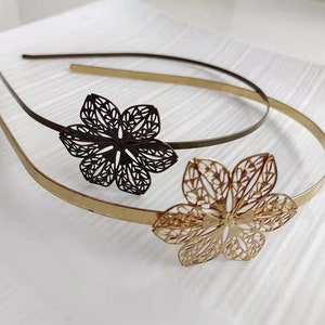 Puede incluir: Dos diademas de metal dorado y negro con diseños decorativos de flores. Las diademas son finas y delicadas.