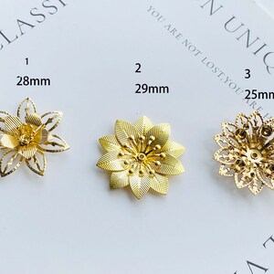Pode incluir: Três enfeites de metal dourado em forma de flor de tamanhos diferentes: 28 mm, 29 mm e 25 mm. Os enfeites têm um design delicado e intrincado com um centro elevado.