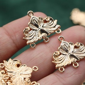 May include: Gold-tone metal connector charms with a floral design. Each charm has three loops for attaching jewelry pieces.