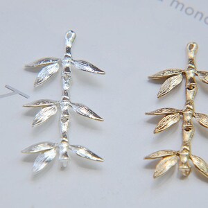May include: Two silver and gold bamboo branch charms, each with three leaves on each branch. The charms are ideal for jewellery making or adding a touch of nature to your crafts.