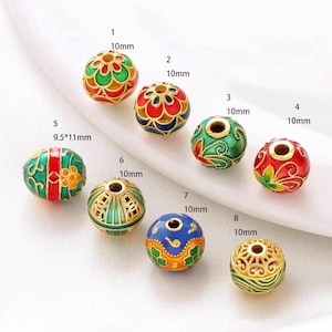 Peut inclure: Huit perles rondes de couleur or avec des motifs en émail coloré. Les perles sont de tailles différentes, allant de 9,5 mm à 10 mm. Chaque perle est numérotée de 1 à 8.