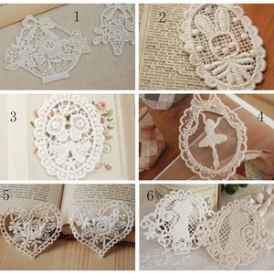 May include: Six white lace appliques with different designs, including a basket, a flower, a ballerina, and a heart. The appliques are arranged in a grid pattern on a white background.