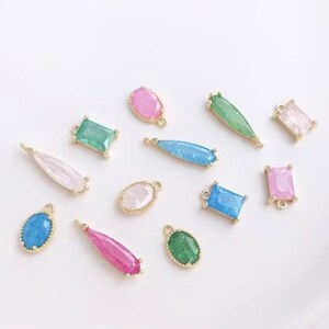 May include: Assortment of colorful, sparkly, and gold-toned charms with various shapes, including ovals, rectangles, and teardrops. These charms are perfect for jewelry making or adding a touch of sparkle to crafts.