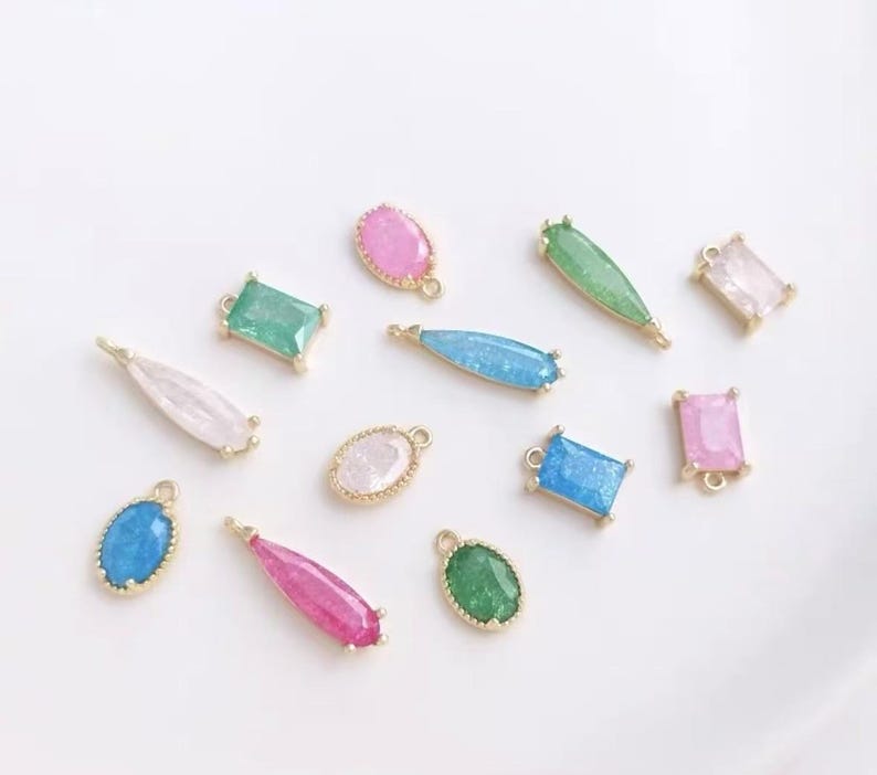 May include: Assortment of colorful, sparkly, and gold-toned charms with various shapes, including ovals, rectangles, and teardrops. These charms are perfect for jewelry making or adding a touch of sparkle to crafts.