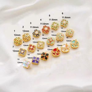 Peut inclure: Assortiment de 18 breloques en forme de fleurs en émail doré avec des accents d'émail de différentes couleurs et de perles. Les breloques mesurent 11,6 mm ou 12 mm.