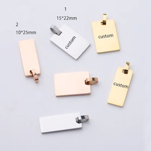 Könnte beinhalten: Vier rechteckige Metalletiketten in Silber, Gold und Roségold mit einem Loch oben. Die Etiketten sind leer, bis auf eines, auf dem "custom" in schwarzer Schrift steht. Die Etiketten sind 10*25mm und 15*22mm groß.