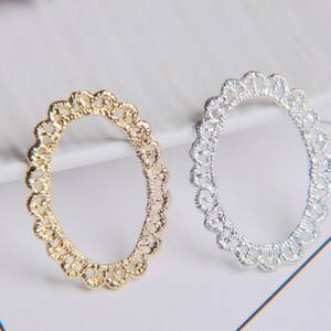 May include: Two oval-shaped metal frames with a delicate, intricate design. One frame is gold and the other is silver.