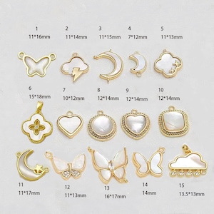 Op de afbeelding: Assortiment van 15 goudkleurige metalen bedels met witte parelmoer inleg. De bedels omvatten vormen zoals vlinder, wolk, halve maan, hart, vierkant en ster. De bedels zijn ongeveer 2,5 tot 5 cm groot.