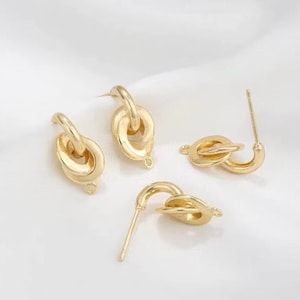 May include: Three pairs of gold-toned earrings with a linked circle design. The earrings are made of metal and have a simple, modern style.