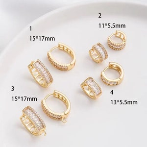 May include: Gold-toned hoop earrings with clear, rectangular and round-cut stones. The image shows four pairs of earrings, with sizes ranging from 11x5.5mm to 15x17mm. The earrings are displayed on a white surface.