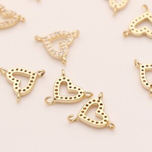 May include: Gold-tone heart-shaped charms with clear crystal accents. The charms have a loop on each side for attaching to jewelry.