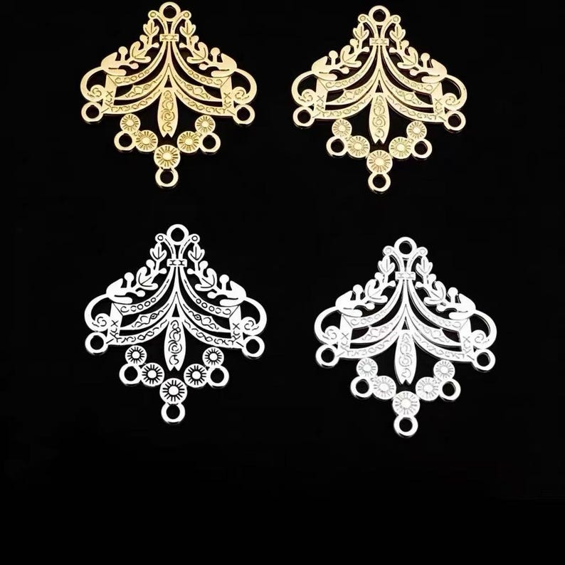 May include: Four decorative metal jewelry connectors featuring an intricate filigree pattern. Two connectors are gold-toned and two are silver-toned. Each piece has a symmetrical, fan-like shape with multiple small circular loops for attachment.