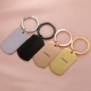 May include: Four keychains with different finishes: silver, black, rose gold, and gold. Each keychain has a rectangular tag with the word "custom" engraved on it.