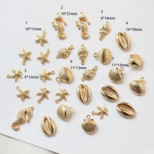 Op de afbeelding: Assortiment van goudkleurige metalen bedels in de vorm van schelpen, zeesterren en zeepaardjes. De bedels zijn ongeveer 2,5 tot 5 cm groot en hebben een gat om aan sieraden of andere knutselwerkjes te bevestigen.