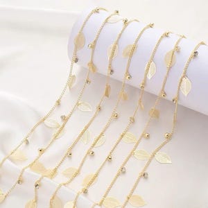 May include: Gold chain with delicate leaf charms and clear crystal beads. The chain is layered and has a delicate, feminine look.