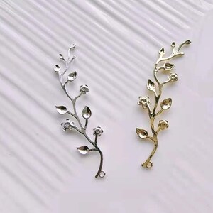 May include: Two metal floral branch embellishments, one gold and one silver, with small flower details. These are perfect for adding a touch of elegance to crafts and jewellery.