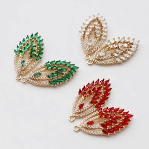 May include: Three pairs of gold-tone metal earring charms with a leaf design. Each pair features a different color of crystal stones: green, white, and red.