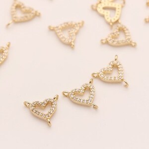 May include: A group of gold-tone heart-shaped charms with clear crystal accents. Each charm has a loop at the top for attaching to jewelry.