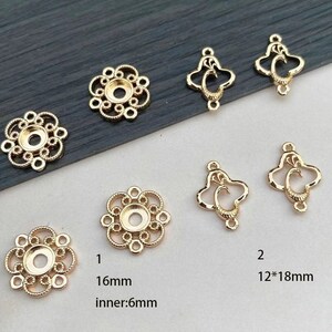 Puede incluir: Hallazgos de joyer&iacute;a dorados en varias formas. La imagen muestra varias piezas, incluyendo engastes en forma de flor con un di&aacute;metro de 16 mm y un di&aacute;metro interior de 6 mm, y colgantes ornamentados en forma de coraz&oacute;n de 12x18 mm. Ideal para la fabricaci&oacute;n de joyas.