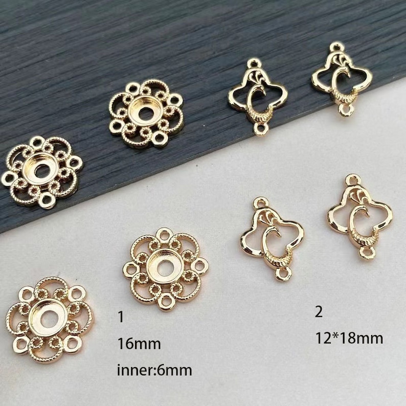 Puede incluir: Hallazgos de joyer&iacute;a dorados en varias formas. La imagen muestra varias piezas, incluyendo engastes en forma de flor con un di&aacute;metro de 16 mm y un di&aacute;metro interior de 6 mm, y colgantes ornamentados en forma de coraz&oacute;n de 12x18 mm. Ideal para la fabricaci&oacute;n de joyas.