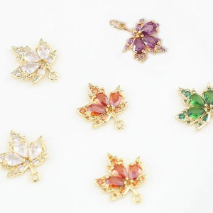 May include: Five gold-tone maple leaf charms with different colored crystal accents. The charms have a loop at the bottom for attaching to jewelry.