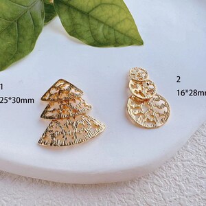May include: Two gold-colored metal earring charms. The first charm is a layered triangle shape with a 25*30mm measurement. The second charm is a layered circle shape with a 16*28mm measurement.