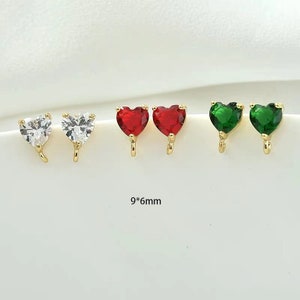 May include: Three pairs of heart-shaped earrings with gold settings. The earrings are available in clear, red, and green.