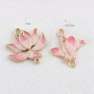 May include: Two pink and gold-coloured lotus flower charms. One charm is 19mm in size, and the other is 12mm by 14mm. The charms have a loop at the top and bottom for attaching to jewellery.