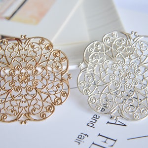 May include: Two decorative metal filigree pieces, one gold and one silver, with intricate floral designs.