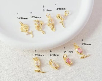 May include: Ten gold flower charms with clear and pink rhinestones. The charms are arranged in two rows on a white surface. The charms are different sizes, ranging from 6 to 12 millimetres in diameter. The charms are labelled with numbers 1 through 8 and their corresponding dimensions.