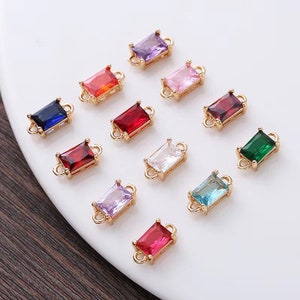 Peut inclure: Assortiment de douze breloques connecteurs dorés avec des pierres précieuses facettées de forme rectangulaire dans différentes couleurs, notamment rouge, rose, bleu, vert et violet.