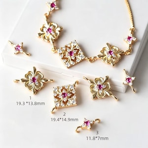 May include: A gold-tone jewelry connector set featuring floral and square shapes with embedded pink and clear stones. Item 1 measures 19.3 by 13.8 mm, item 2 measures 19.4 by 14.9 mm, and item 3 measures 11.8 by 7 mm. Includes a matching necklace chain.