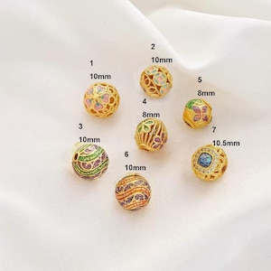 Peut inclure: Dix perles dorées avec des motifs en émail coloré. Les perles ont un diamètre de 8 mm, 10 mm et 10,5 mm.