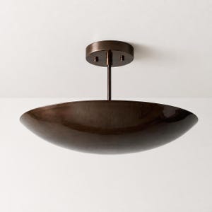 May include: A dark bronze semi-flush mount ceiling light fixture featuring a wide, shallow, bowl-shaped shade suspended from a cylindrical canopy by a single vertical rod. The metal surface has a smooth, reflective finish with subtle tonal variations.