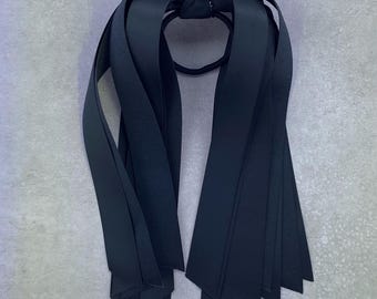 May include: Black ribbon hair tie with multiple long streamers. The streamers are tied together at the top with a knot and the hair tie is made of elastic.