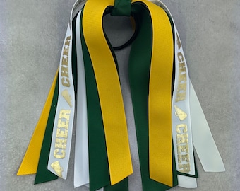 May include: Gold and green cheer bow with white ribbons and the word "CHEER" printed in gold on the ribbons.