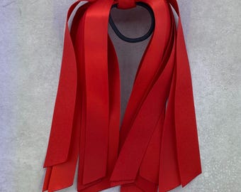 May include: Red ribbon hair tie with multiple long streamers. The hair tie is made of a black elastic band.