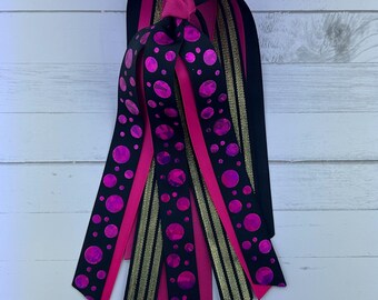 May include: A set of pink and black ribbon with a gold ribbon. The black ribbon has pink polka dots. The ribbons are tied together at the top.