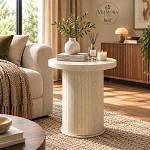 May include: A cylindrical side table with a speckled off-white finish and vertical fluted detailing. The table features a flat circular top and a matching circular base, providing a stable foundation for the decorative items placed on its surface.