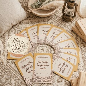 Può includere: Una collezione di carte traguardo rettangolari con un bordo giallo senape e una base con motivo marrone. Ogni carta presenta il testo francese 'Aujourd'hui' e traguardi come 'J'ai dit papa' o 'J'ai mangé ma première purée' con righe per data e ora.