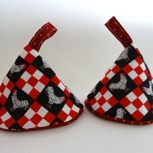May include: Two red and white checkered pot holders with a black rooster design and a red loop handle.