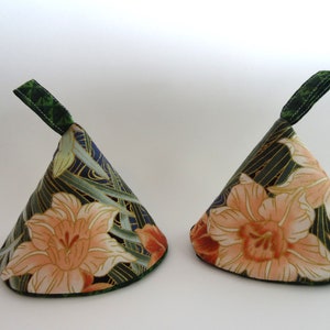 May include: Two cone-shaped pot holders with a floral print. The fabric is a dark green, gold, and cream color with a large pink flower design. Each pot holder has a green loop handle.