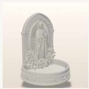 May include: A white, matte-finish wall-mounted holy water font featuring a central relief of the Virgin Mary surrounded by a sunburst halo and sculpted roses. The arched backplate includes ornate scrollwork, and the basin has a circular base.