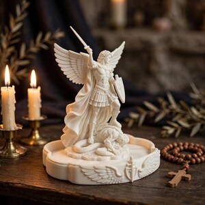 May include: A white, off-white, or cream-colored resin statue depicting an angel with large wings, wearing armor, holding a sword raised high, and a shield, standing over a defeated figure on a decorative base with carved wing and shield motifs.