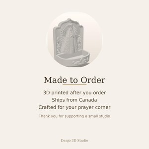 Puede incluir: Una pila de agua bendita de color gris claro impresa en 3D con una escultura en relieve de la Virgen Mar&iacute;a con corona y rayos de luz. El cuenco es semicircular con volutas decorativas en la base, sobre un fondo claro y liso.