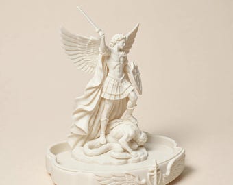 May include: A cream-colored statue of an archangel with large wings, wearing armor and holding a sword raised high in one hand and a shield in the other, standing over a fallen figure on a circular base decorated with carved wings and a sword.