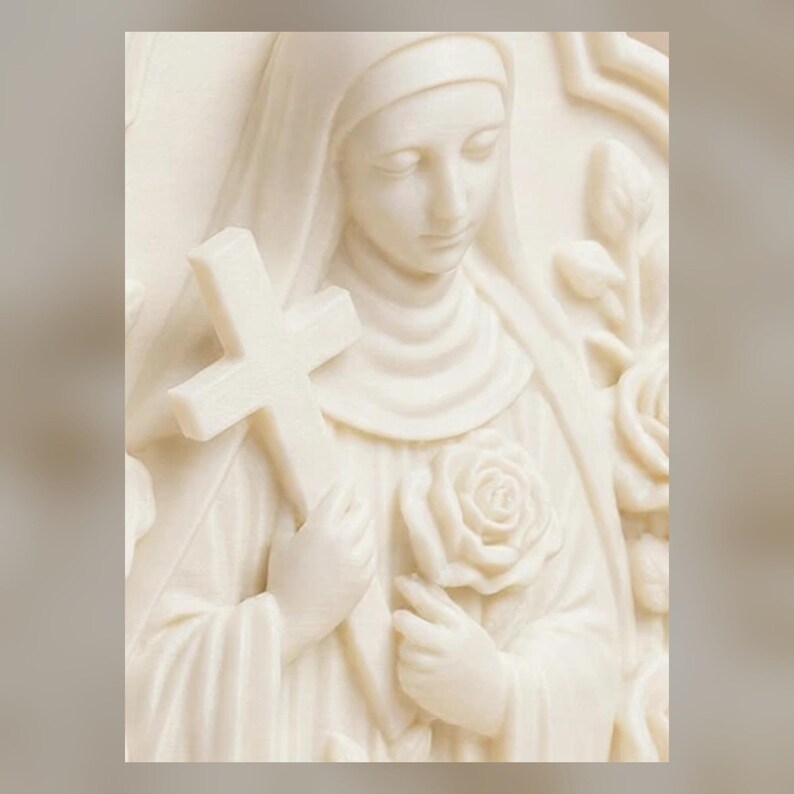 May include: A cream-colored relief sculpture depicting a figure wearing a veil and habit. The figure holds a plain cross in one hand and a single rose in the other, with additional rose blossoms and foliage carved into the background panel.