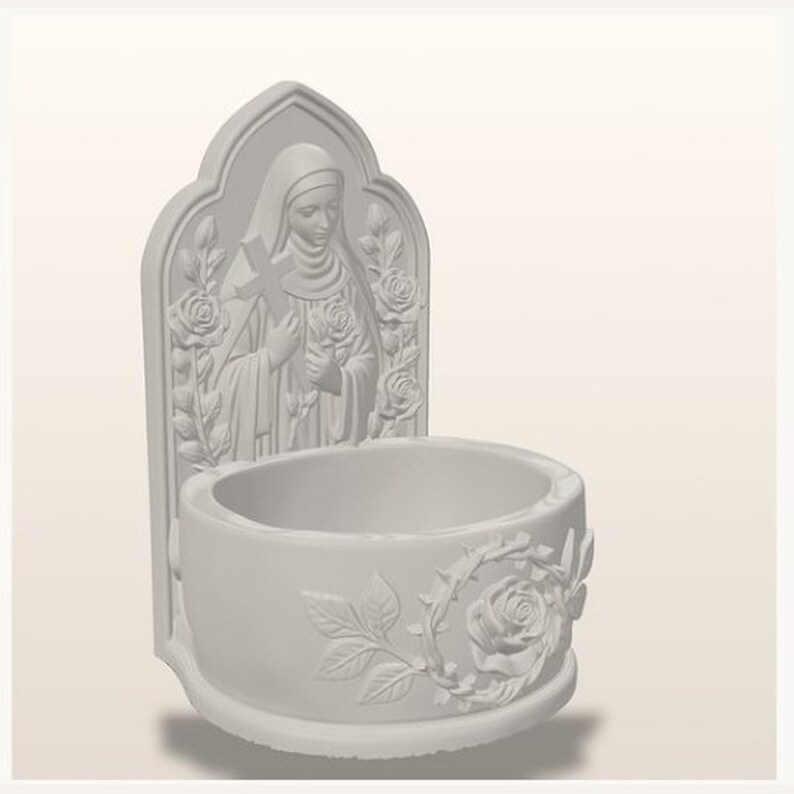 May include: A white wall-mounted holy water font featuring a relief sculpture of a figure in a habit holding a cross and roses. The basin is circular with a relief of a rose surrounded by a crown of thorns on the front exterior surface.