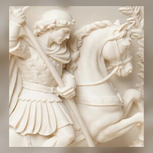 K&ouml;nnte beinhalten: Ein cremefarbenes Steinrelief, das eine Figur in klassischer R&uuml;stung mit einem langen Speer auf einem Pferd darstellt. Die Figur tr&auml;gt eine Tunika und einen Umhang, w&auml;hrend das Pferd im Profil mit detaillierter M&auml;hne und Zaumzeug abgebildet ist.