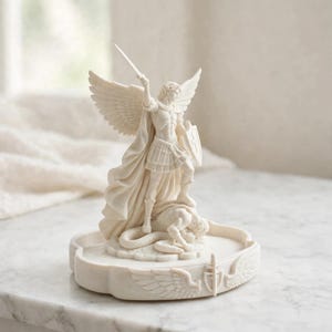 May include: A cream-colored statue of an angel with large wings, wearing armor and a flowing cape, holding a sword raised high and a shield. The angel stands over a serpent figure on a circular base decorated with carved wings and a shield emblem.